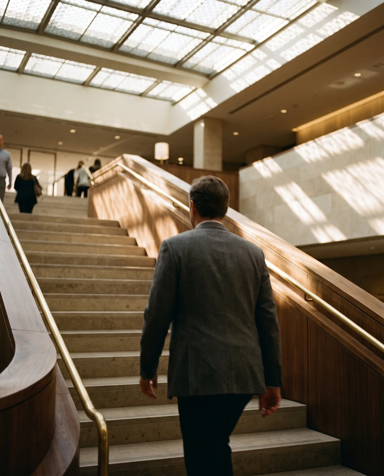 An executive climbing a wide staircase in a daylit atrium