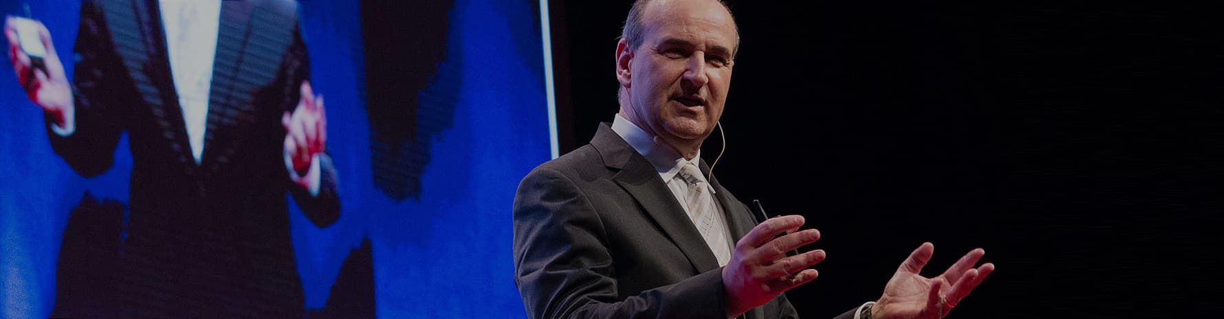 John Mattone on stage, hands open to the audience, closing the one-year journey at the Vision Summit